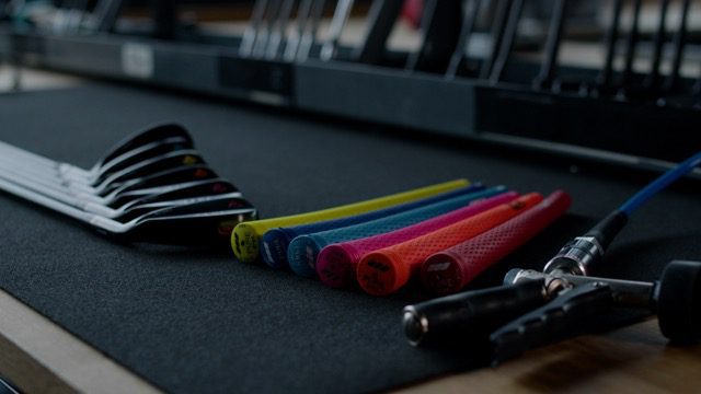 Image of different golf club components laying next to each other on a workbench.