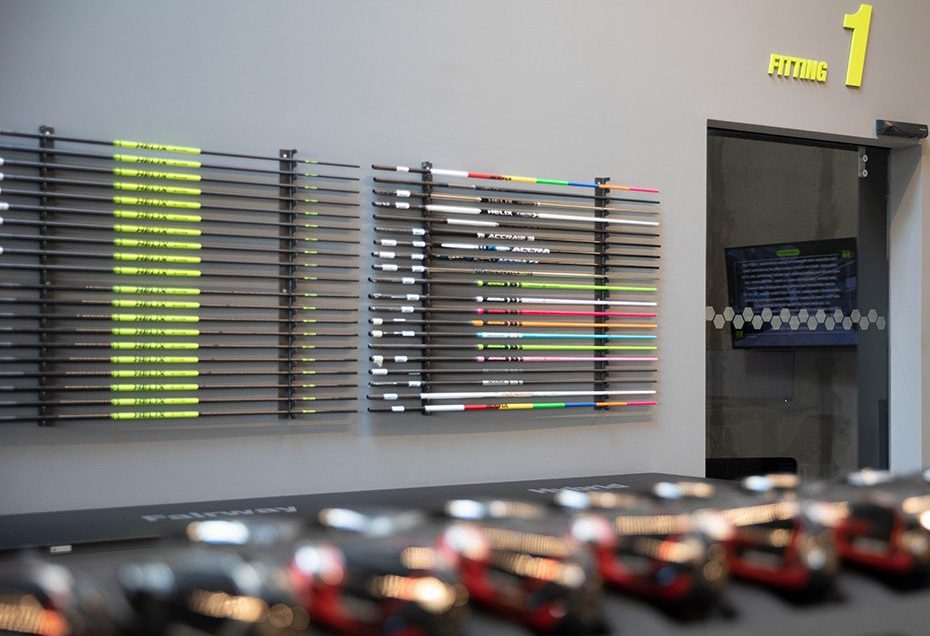 Image of a colorful golf club shaft display on the wall of an indoor fitting studio.